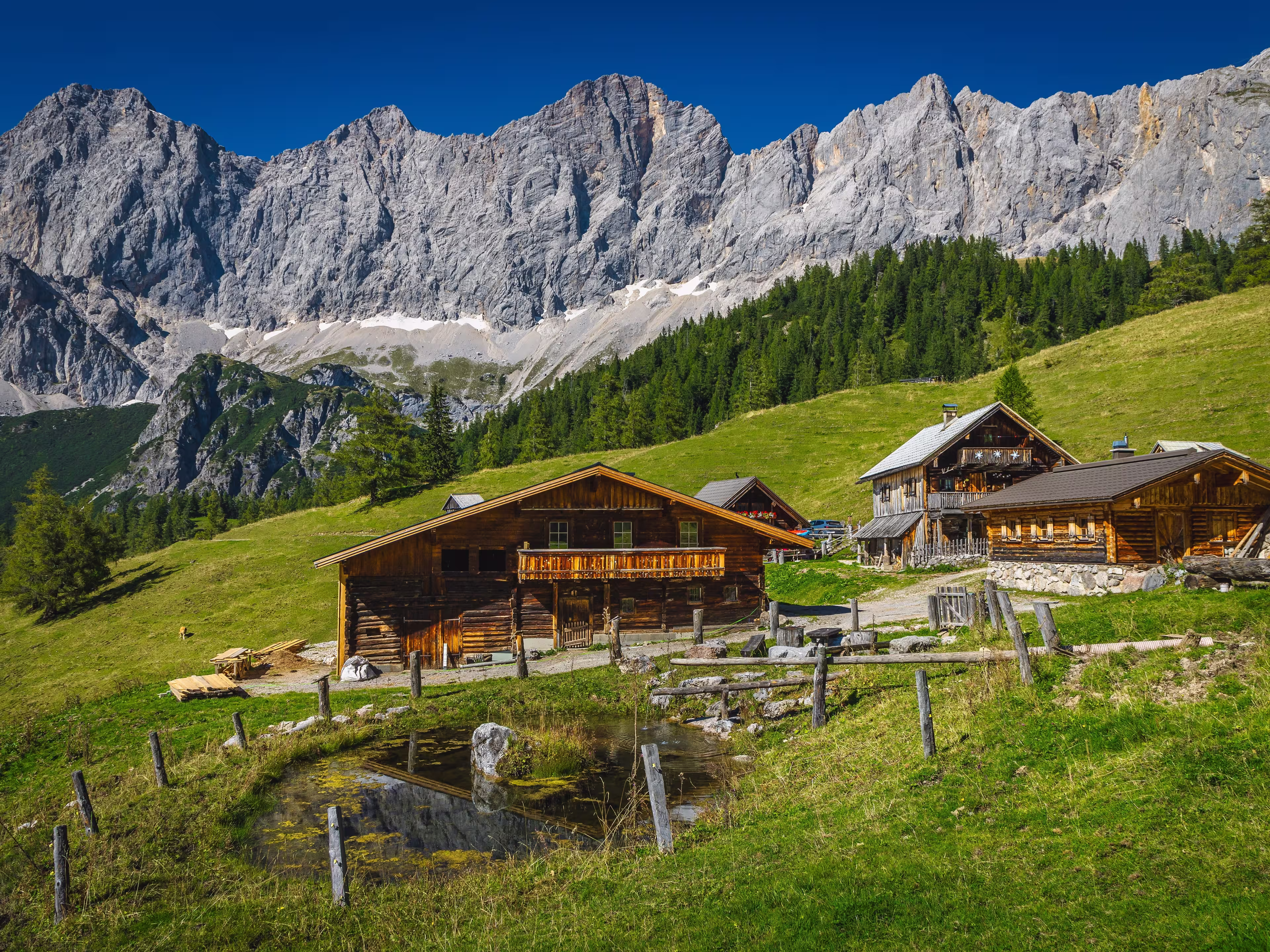 Admirable alpine landscape, wooden log houses on the slope and picturesque high mountains in background, Dachstein mountain group, Ramsau am Dachstein, Austria, Europe