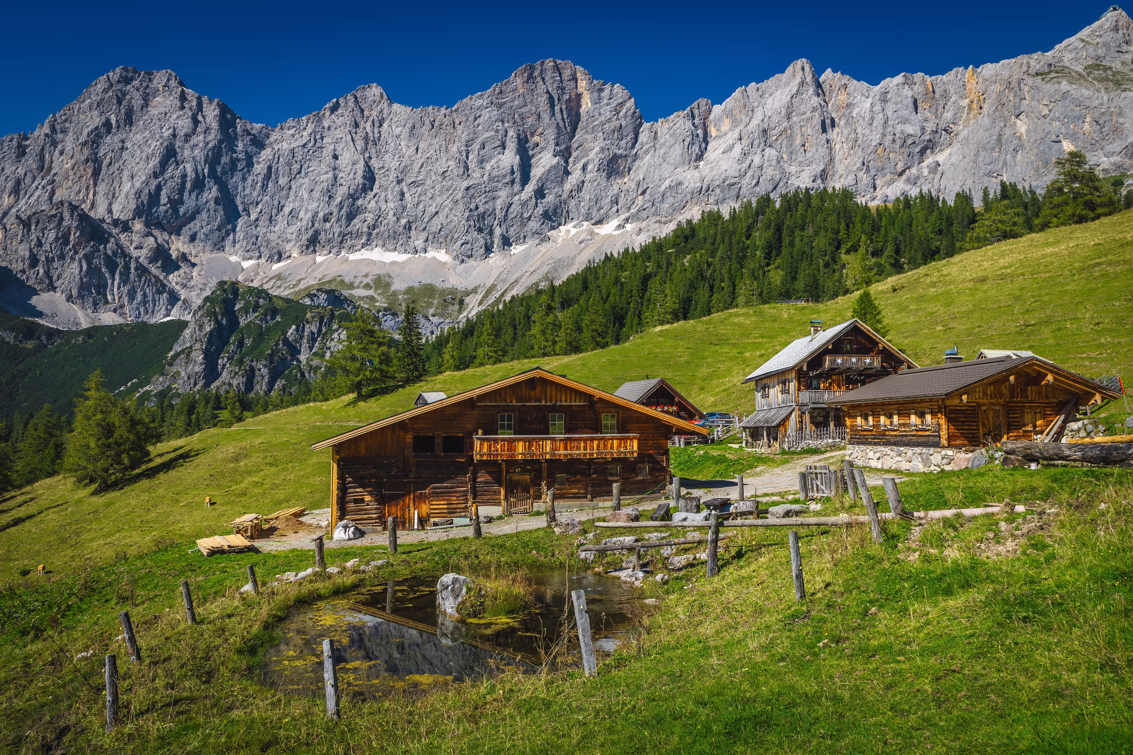 Admirable alpine landscape, wooden log houses on the slope and picturesque high mountains in background, Dachstein mountain group, Ramsau am Dachstein, Austria, Europe