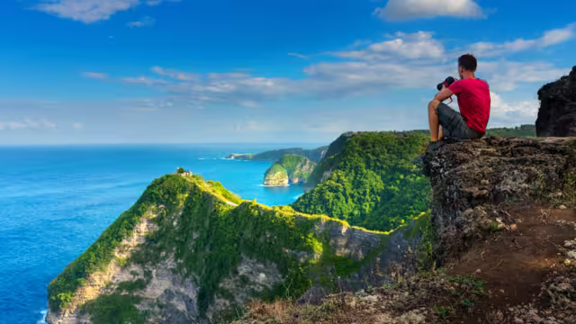 Traveler look at the ocean and rocks. Travel and active life concept. Adventure and travel on Bali, Indonesia.