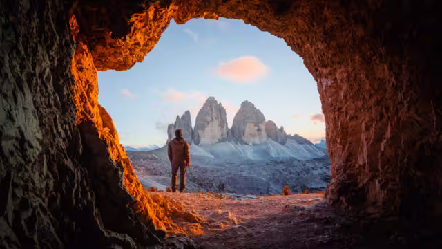 Tre Cime Di Lavaredo peaks in incredible orange sunset light. View from the cave in mountain against Three peaks of Lavaredo, Dolomite Alps, Italy, Europe. Landscape photography