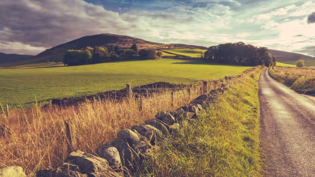 Country Road Or Lane And Dry Stone Wall Through Scottish Rural Lanscape At Dusk