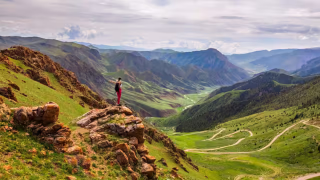 Intrepid traveller stops for a lookout while trekking in the Tien Shan Mountains of Kyrgyzstan