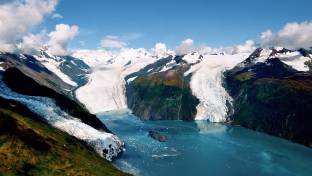 Aerial shot of three majestic glaciers calving into the beautiful azure blue waters of Prince William Sound, Kenai Peninsula. Icebergs float in the water below - Alaska