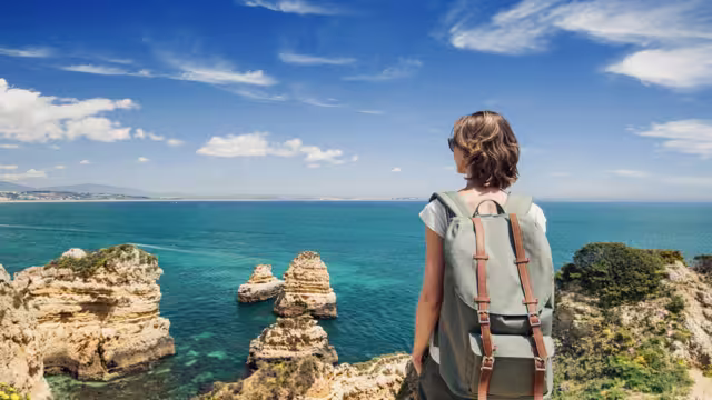 Female traveler looking at the sea in Lagos town, Algarve region, Portugal. Travel and active lifestyle concept