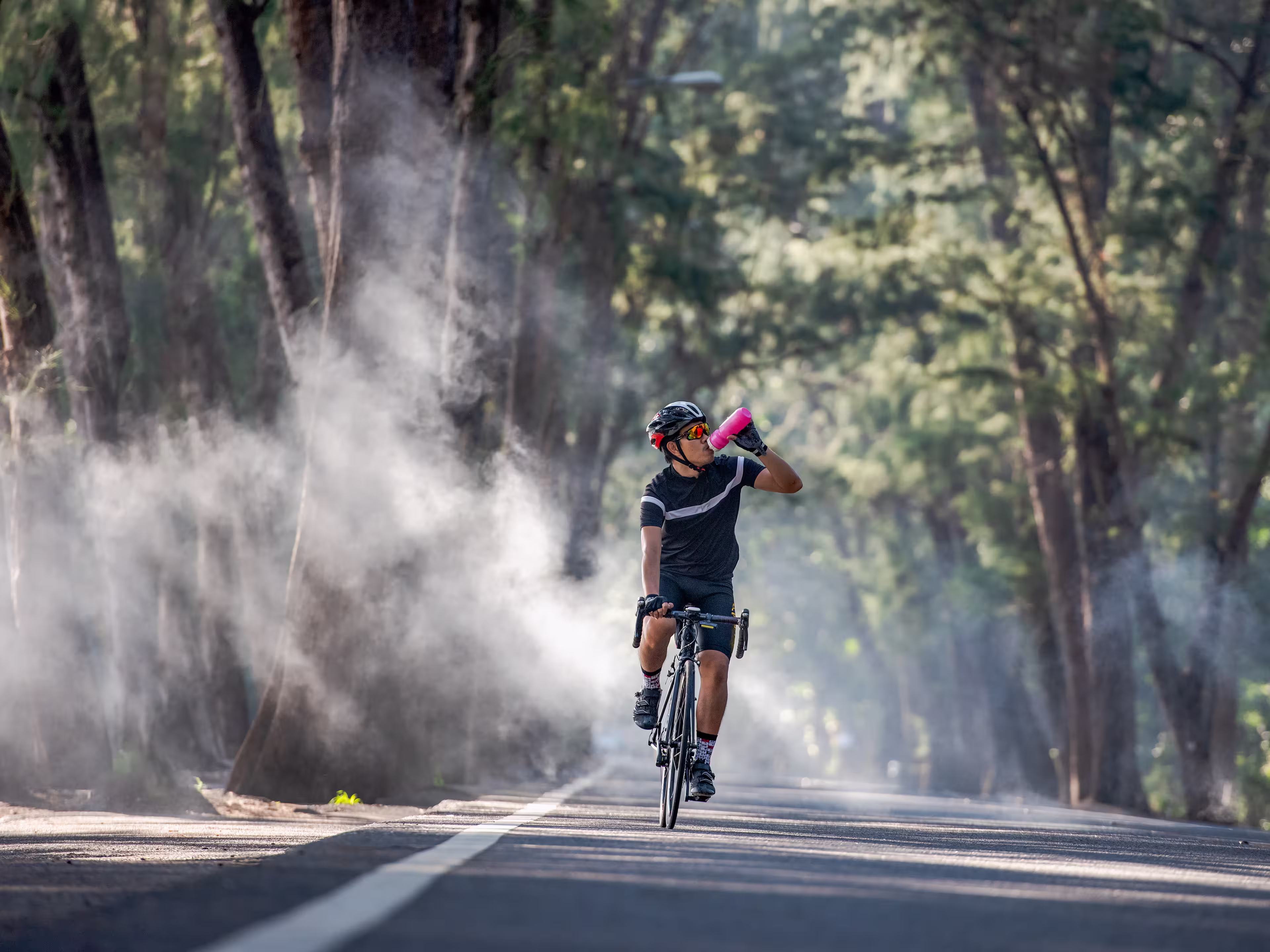 Cyclist is drinking water from the sport bottle