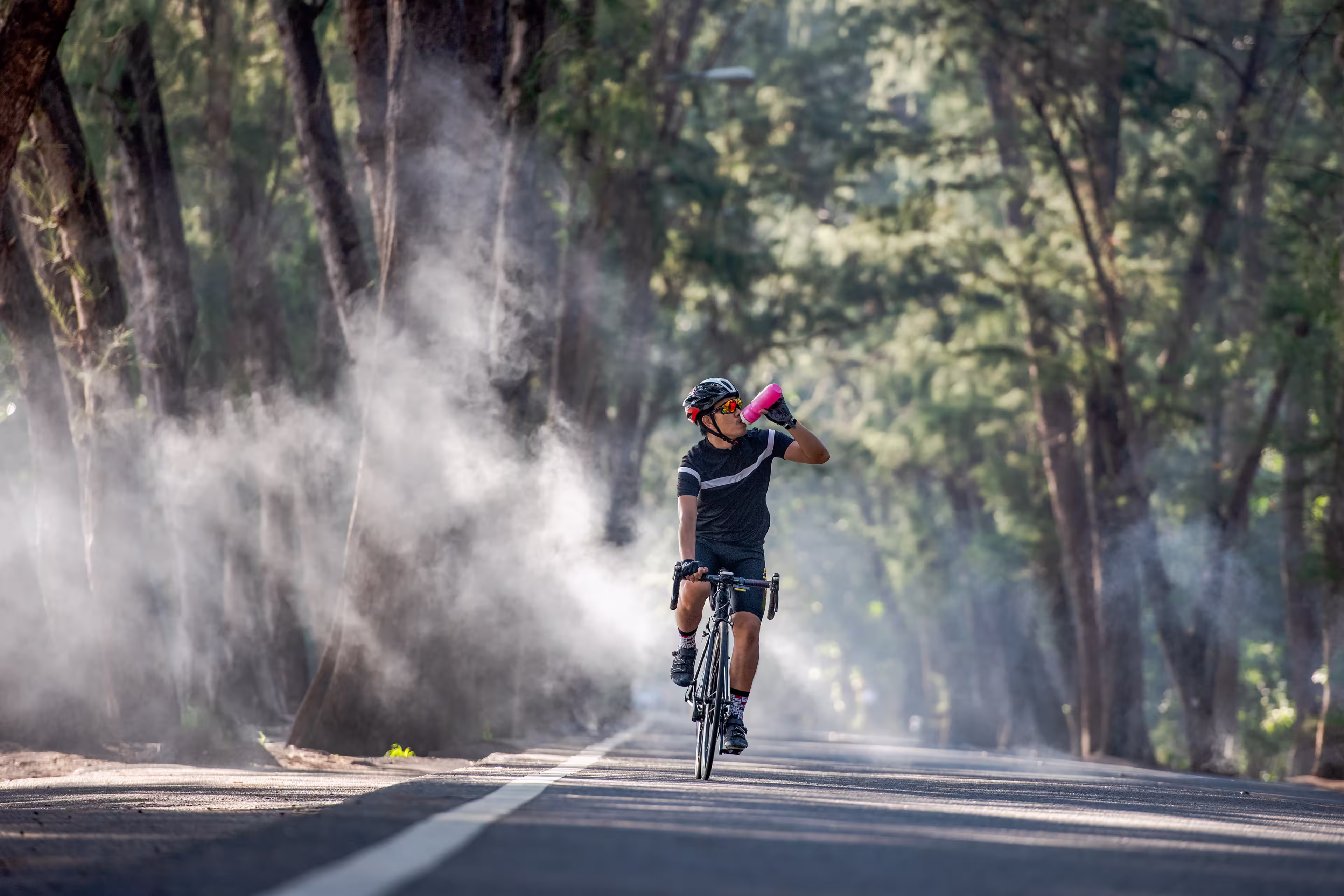 Cyclist is drinking water from the sport bottle