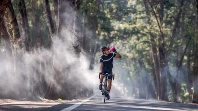 Cyclist is drinking water from the sport bottle