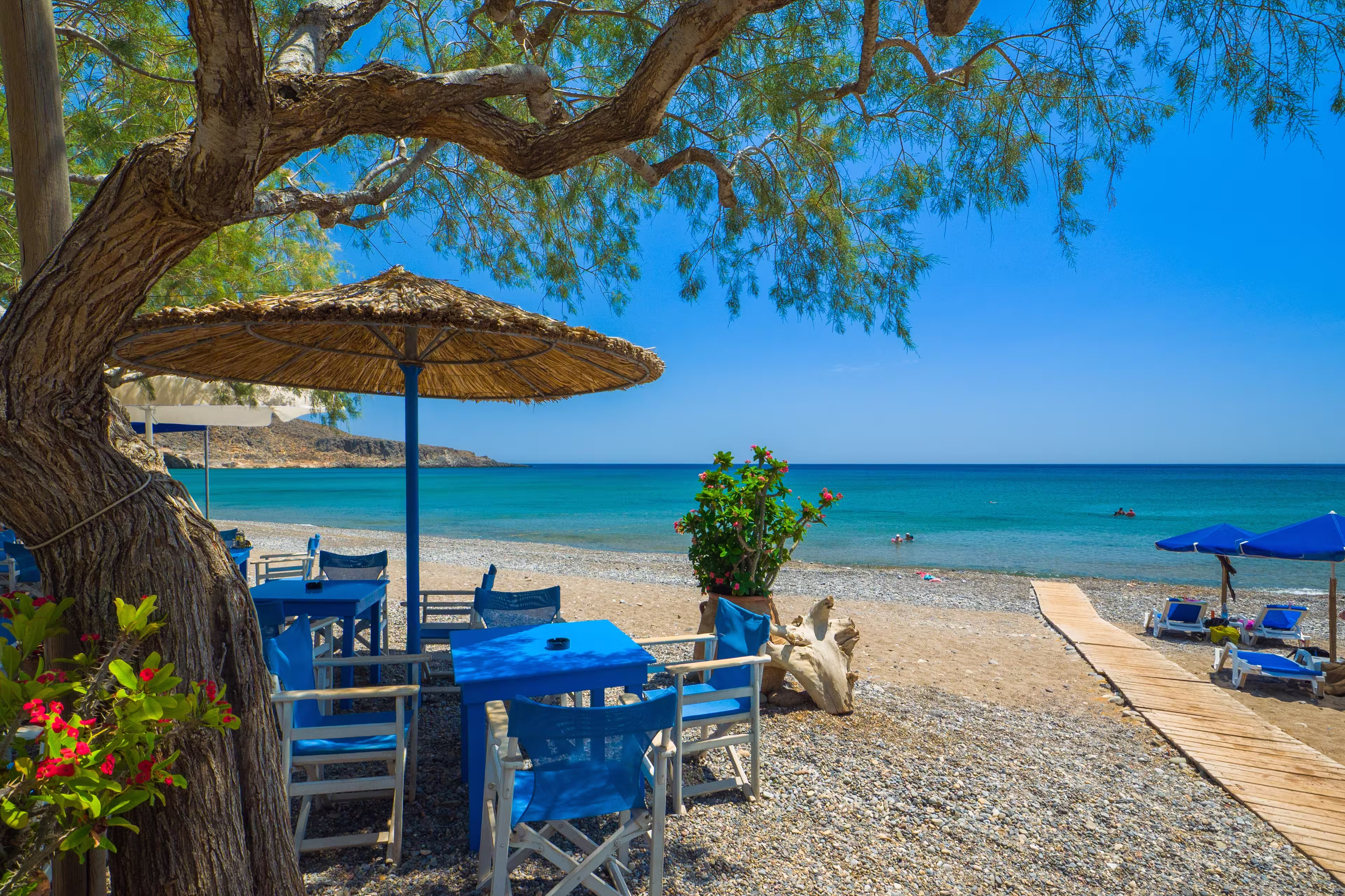 Parasols and tables with chairs set up on a quiet resort beach (Kato Zakros beach, Crete, Greece)