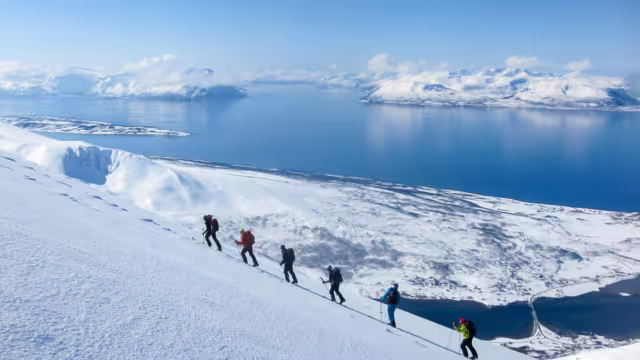 A group of people randonee ski walking high above the fjords. Lyngen Alps, Norway