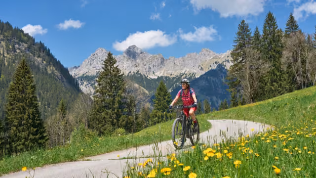 nice senior woman riding her electric mountain bike on the old Gaicht Pass road from Lech Valley up to the Tannheim Valley in Tyrol, Austria