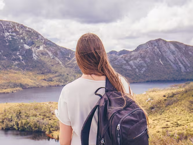 Traveller stands in front of Lake St Clair and Cradle Mountain