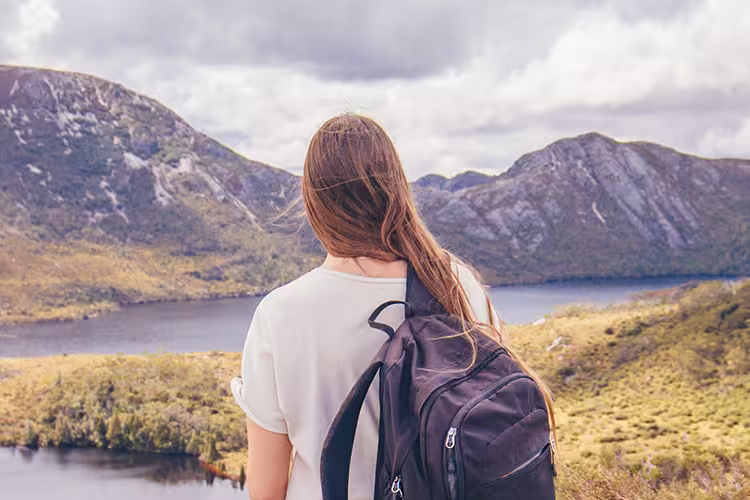 Traveller stands in front of Lake St Clair and Cradle Mountain