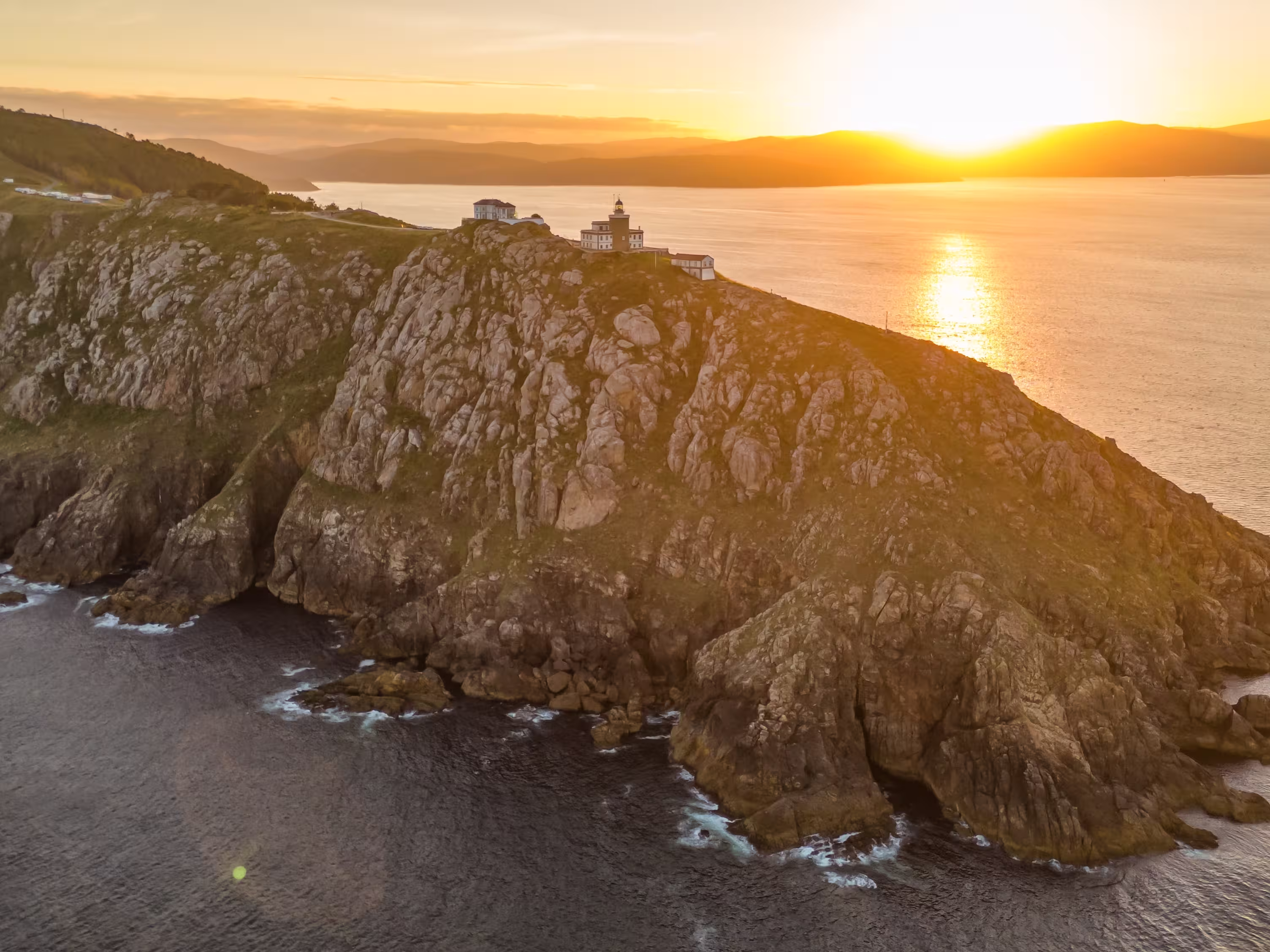 Aerial view of the Faro de Fisterra lighthouse on Cape Finisterre at sunrise, Costa de la Muerte, Galicia, northern Spain. The final destination of the Camino de Santiago pilgrimage route