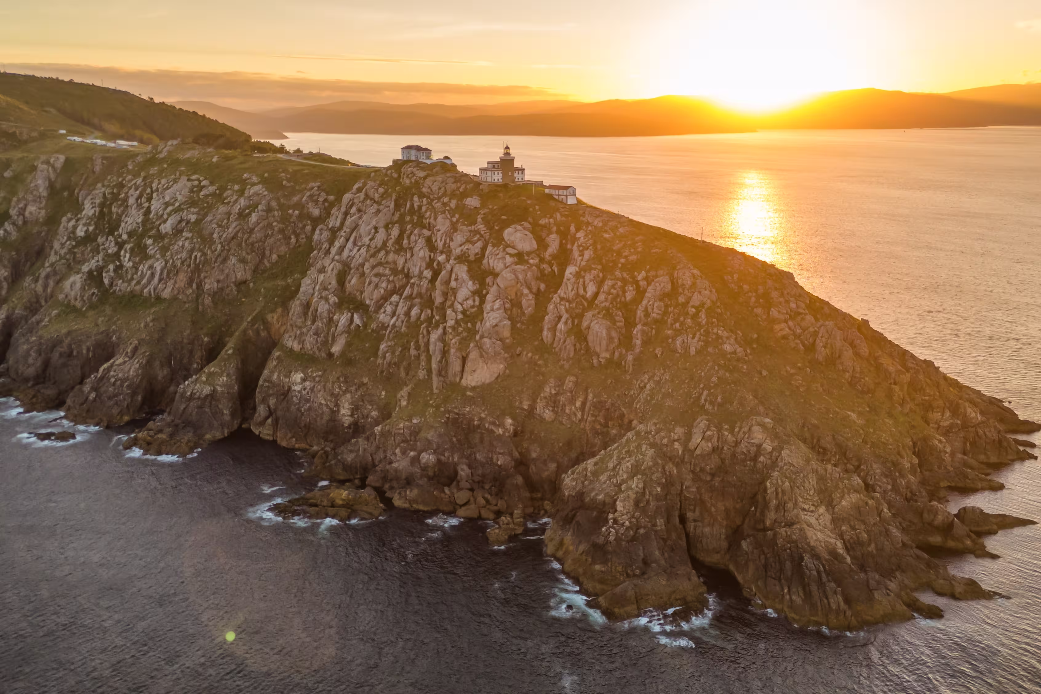 Aerial view of the Faro de Fisterra lighthouse on Cape Finisterre at sunrise, Costa de la Muerte, Galicia, northern Spain. The final destination of the Camino de Santiago pilgrimage route