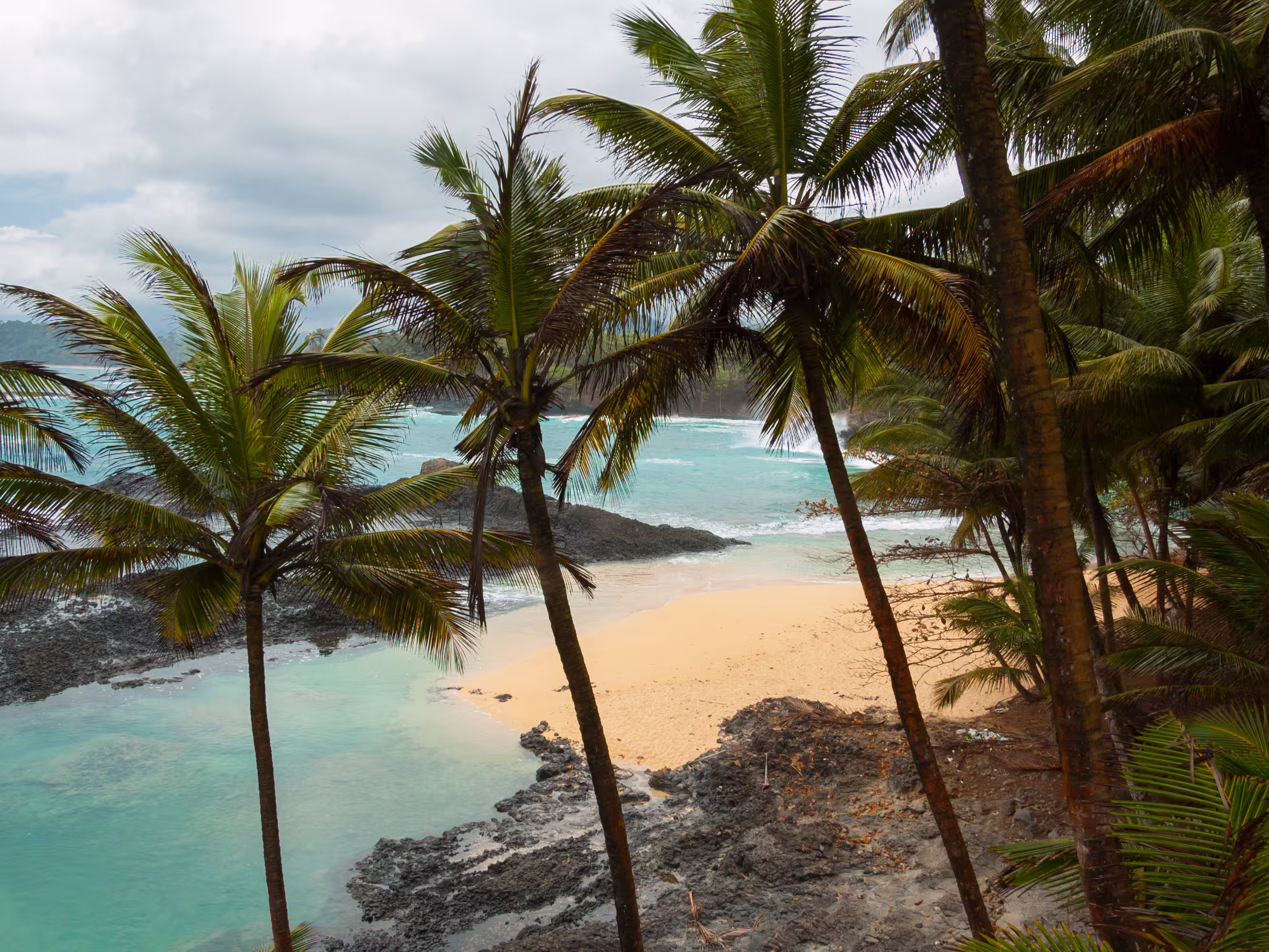 Tropical beach with palm trees and pristine blue sea. Praia Piscina, Sao tome and Principe.