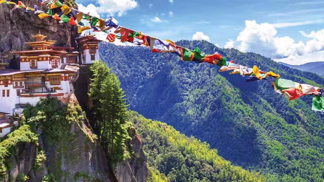 HEPIC - View of the Tiger Monastery and colourful flags on a hill in Bhutan