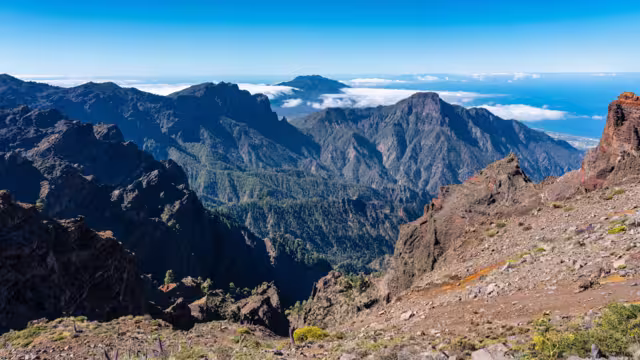 Impressive mountain range of volcanic rock with a volcano emerging from the clouds, La Palma, Canary Islands.