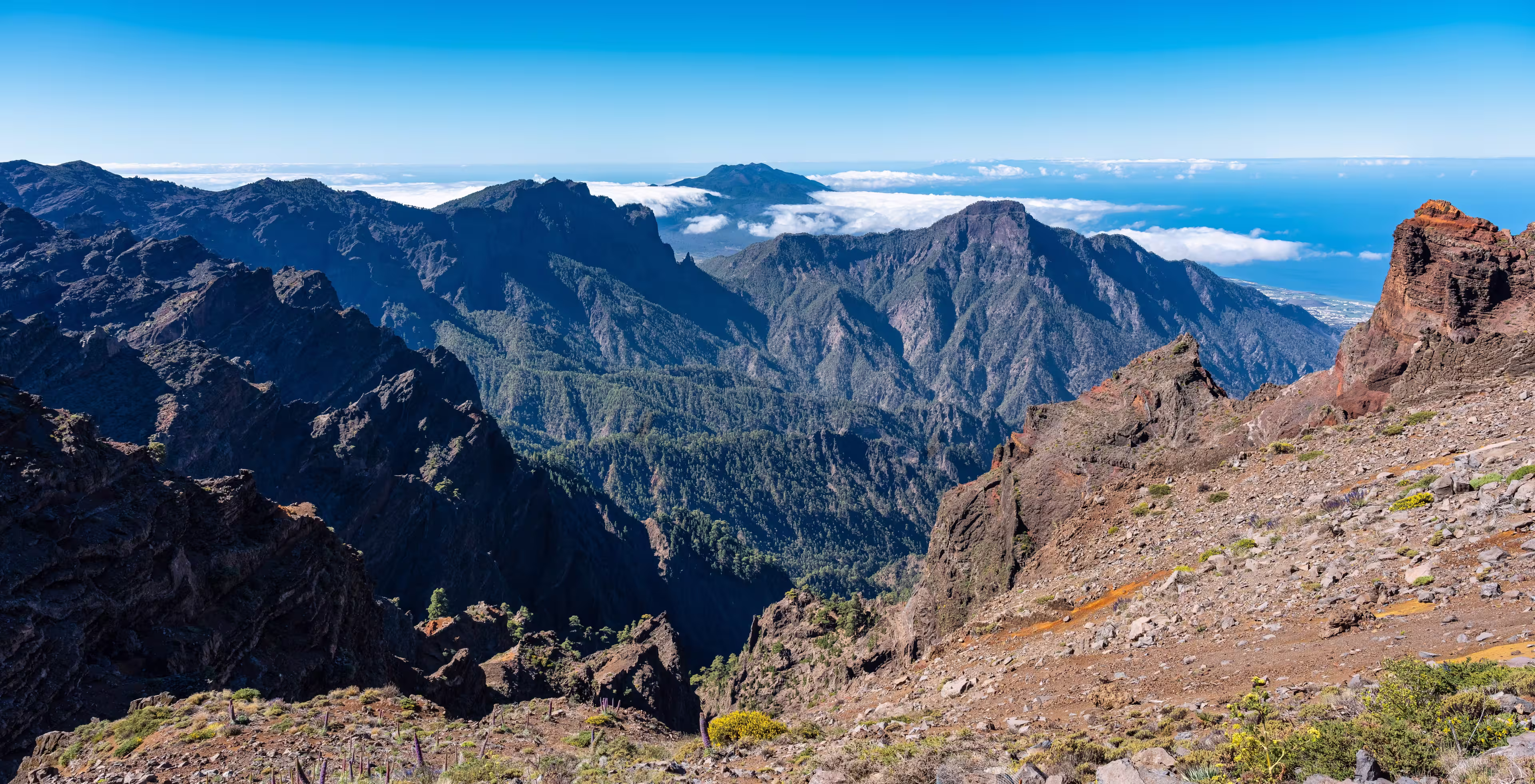 Impressive mountain range of volcanic rock with a volcano emerging from the clouds, La Palma, Canary Islands.