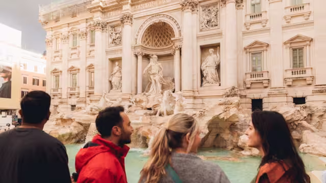 View from behind four travellers viewing the Trevi Fountain, Rome, Italy