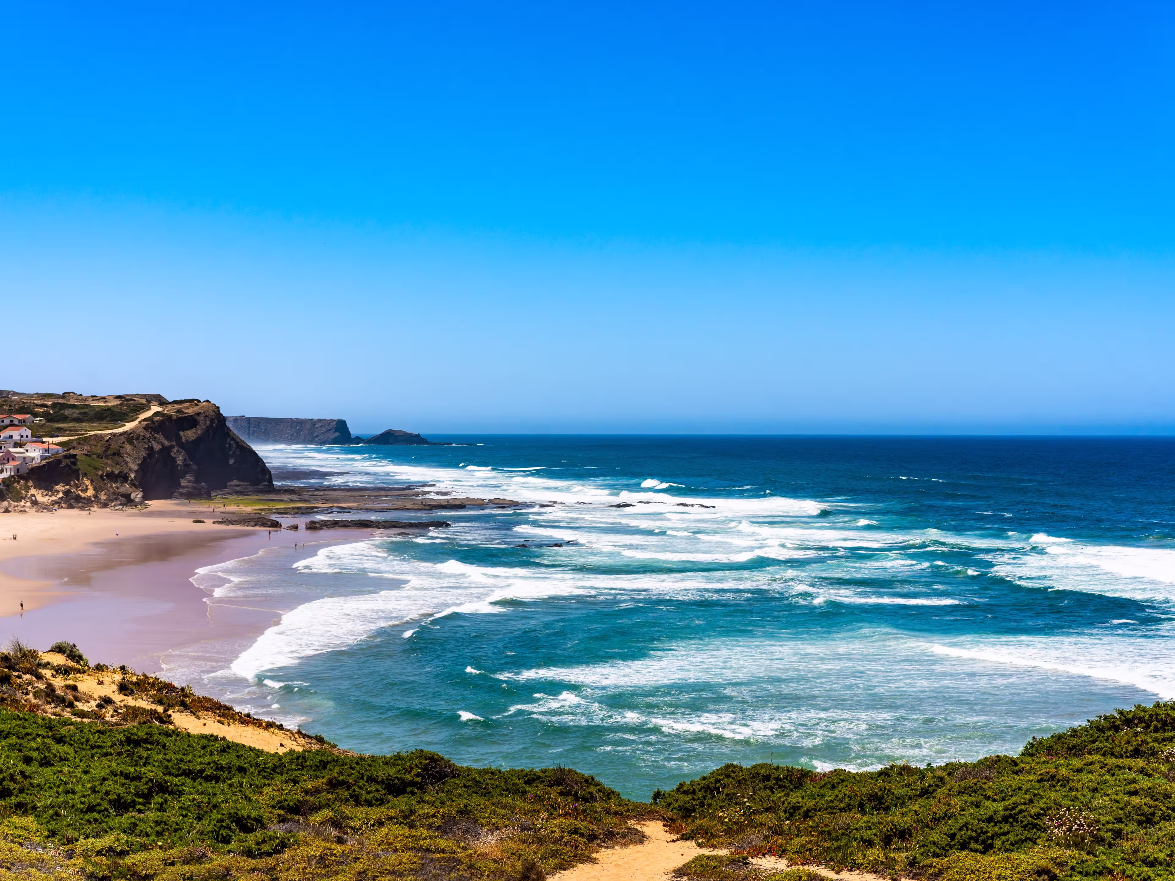 Sandy beach and turquoise ocean. Portugal, Algarve, Monte Clerigo beach. Seascape with big waves on ocean