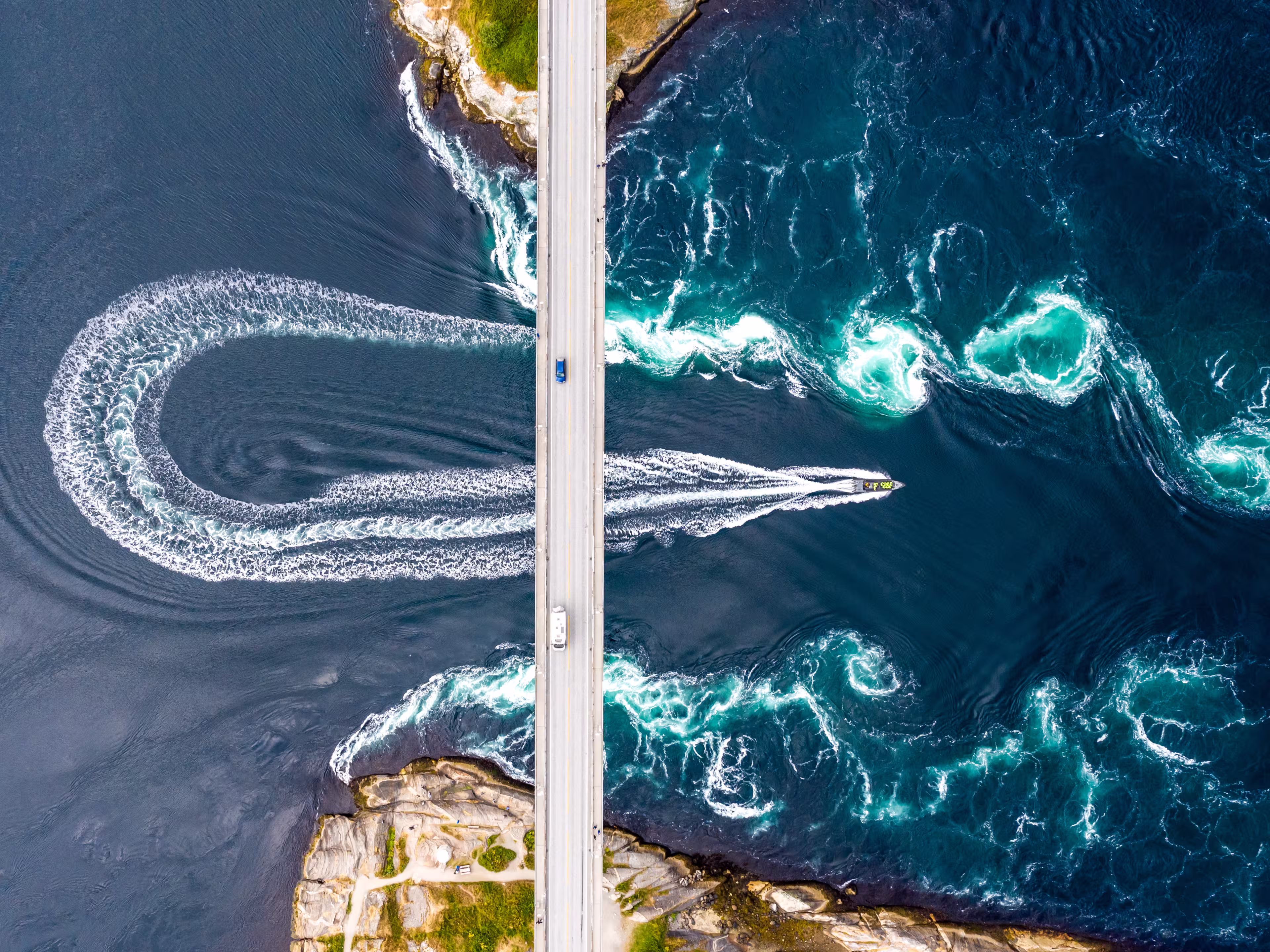 Aerial top down view of world's strongest tidal whirlpools - maelstroms - between Saltfjorden and Skjerstad Fjord  observed by tourists from power boat in Saltstraumen, Norway