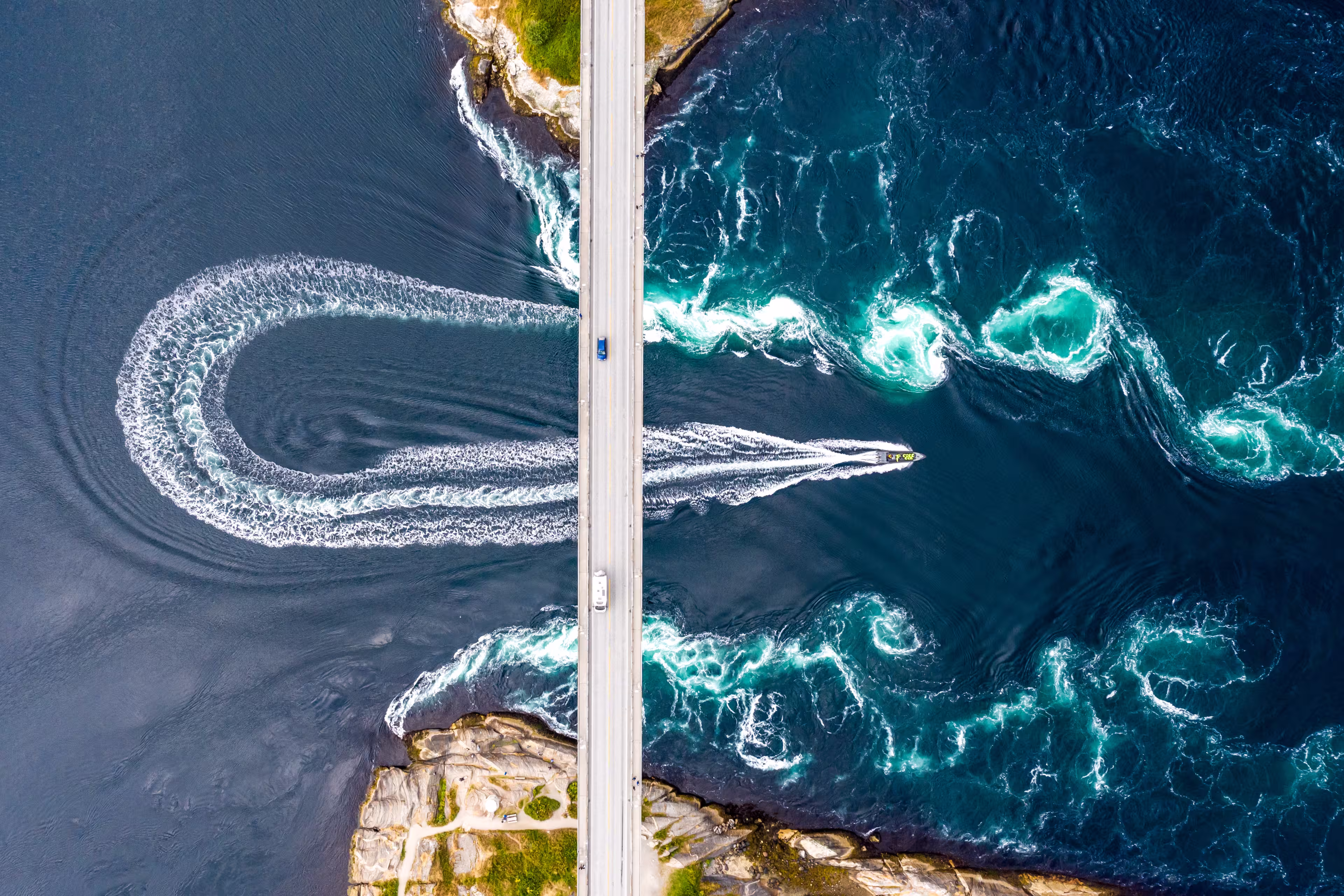 Aerial top down view of world's strongest tidal whirlpools - maelstroms - between Saltfjorden and Skjerstad Fjord observed by tourists from power boat in Saltstraumen, Norway