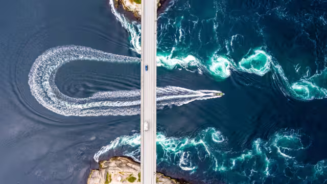 Aerial top down view of world's strongest tidal whirlpools - maelstroms - between Saltfjorden and Skjerstad Fjord  observed by tourists from power boat in Saltstraumen, Norway