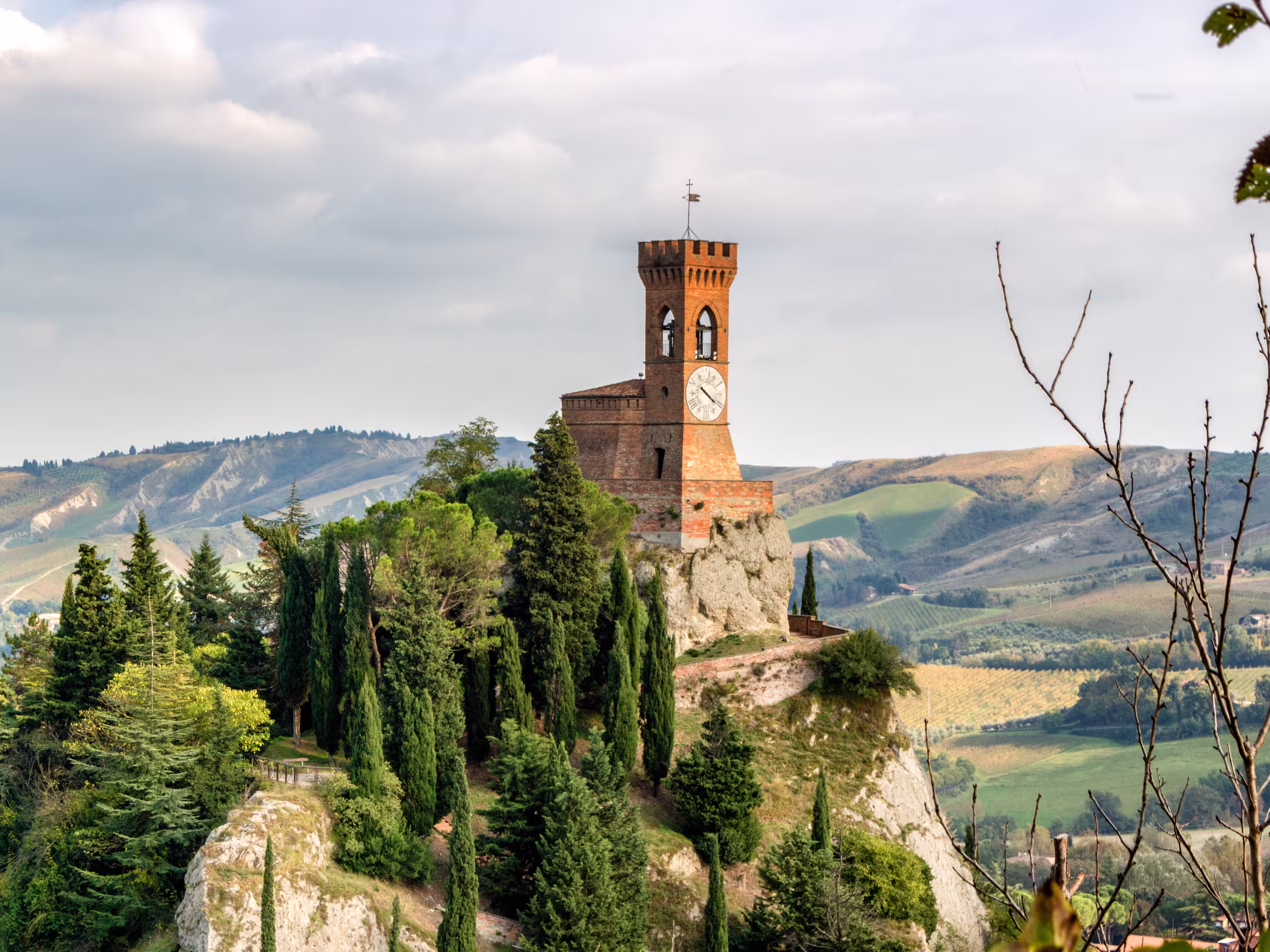 The medieval clock tower surrounded by cypress and other trees, viewed from the Rock of Brisighella in Emilia Romagna, Italy.