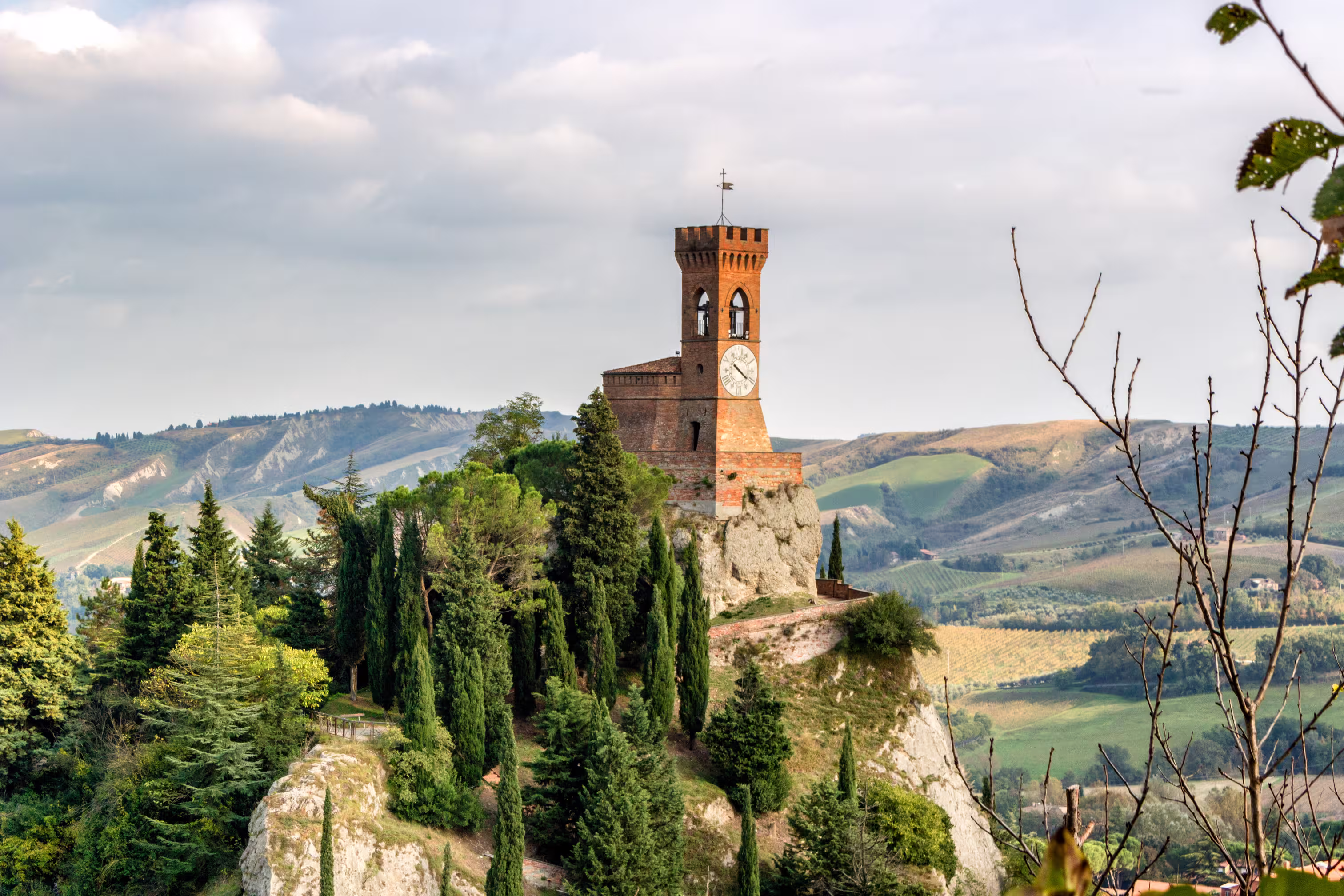 The medieval clock tower surrounded by cypress and other trees, viewed from the Rock of Brisighella in Emilia Romagna, Italy.