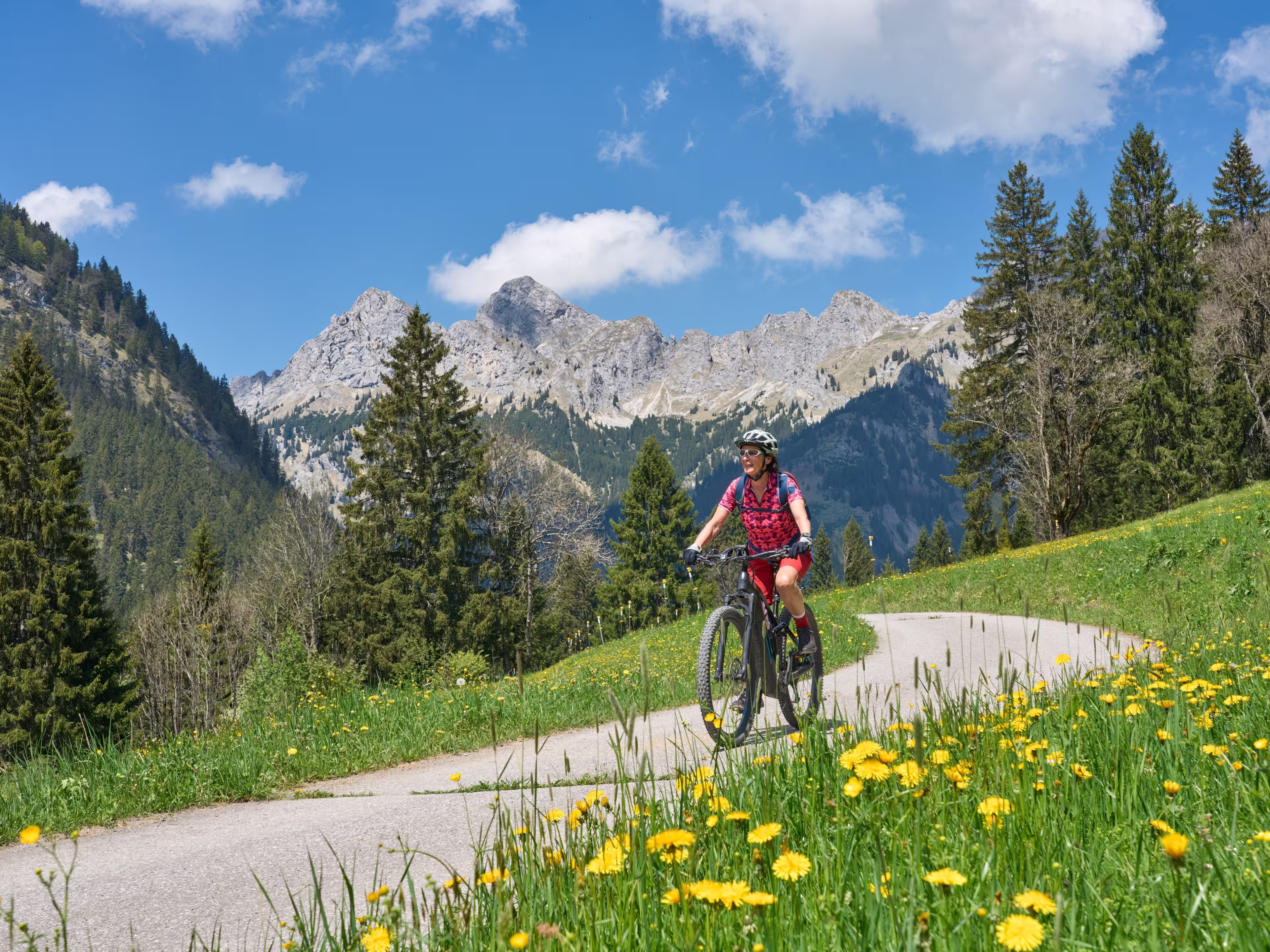 nice senior woman riding her electric mountain bike on the old Gaicht Pass road from Lech Valley up to the Tannheim Valley in Tyrol, Austria