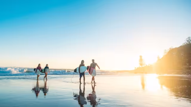 18 to 35 year old Travellers come in from a morning surf on the NSW coast at sunrise
