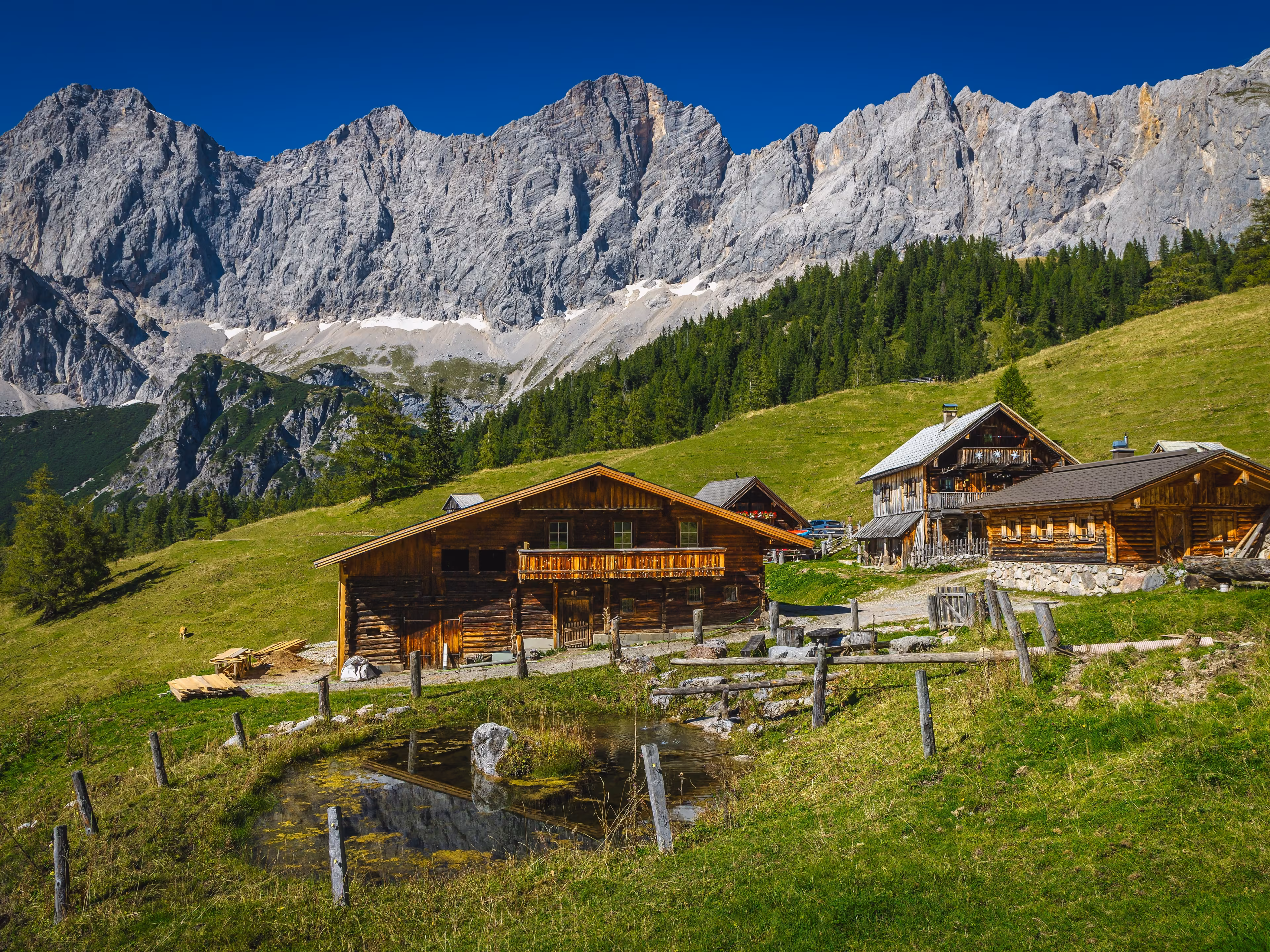 Admirable alpine landscape, wooden log houses on the slope and picturesque high mountains in background, Dachstein mountain group, Ramsau am Dachstein, Austria, Europe