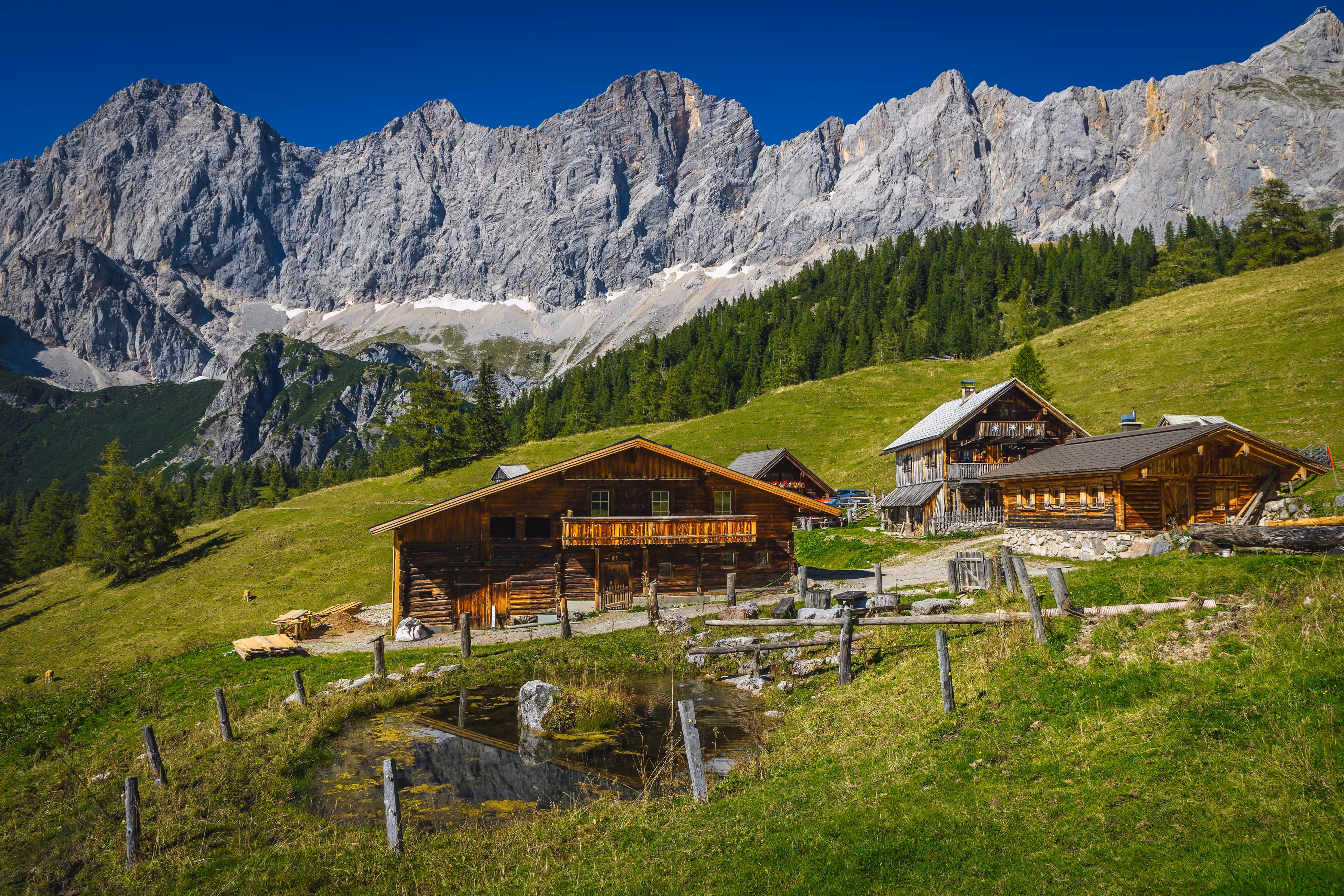 Admirable alpine landscape, wooden log houses on the slope and picturesque high mountains in background, Dachstein mountain group, Ramsau am Dachstein, Austria, Europe