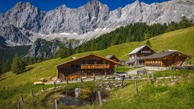 Admirable alpine landscape, wooden log houses on the slope and picturesque high mountains in background, Dachstein mountain group, Ramsau am Dachstein, Austria, Europe