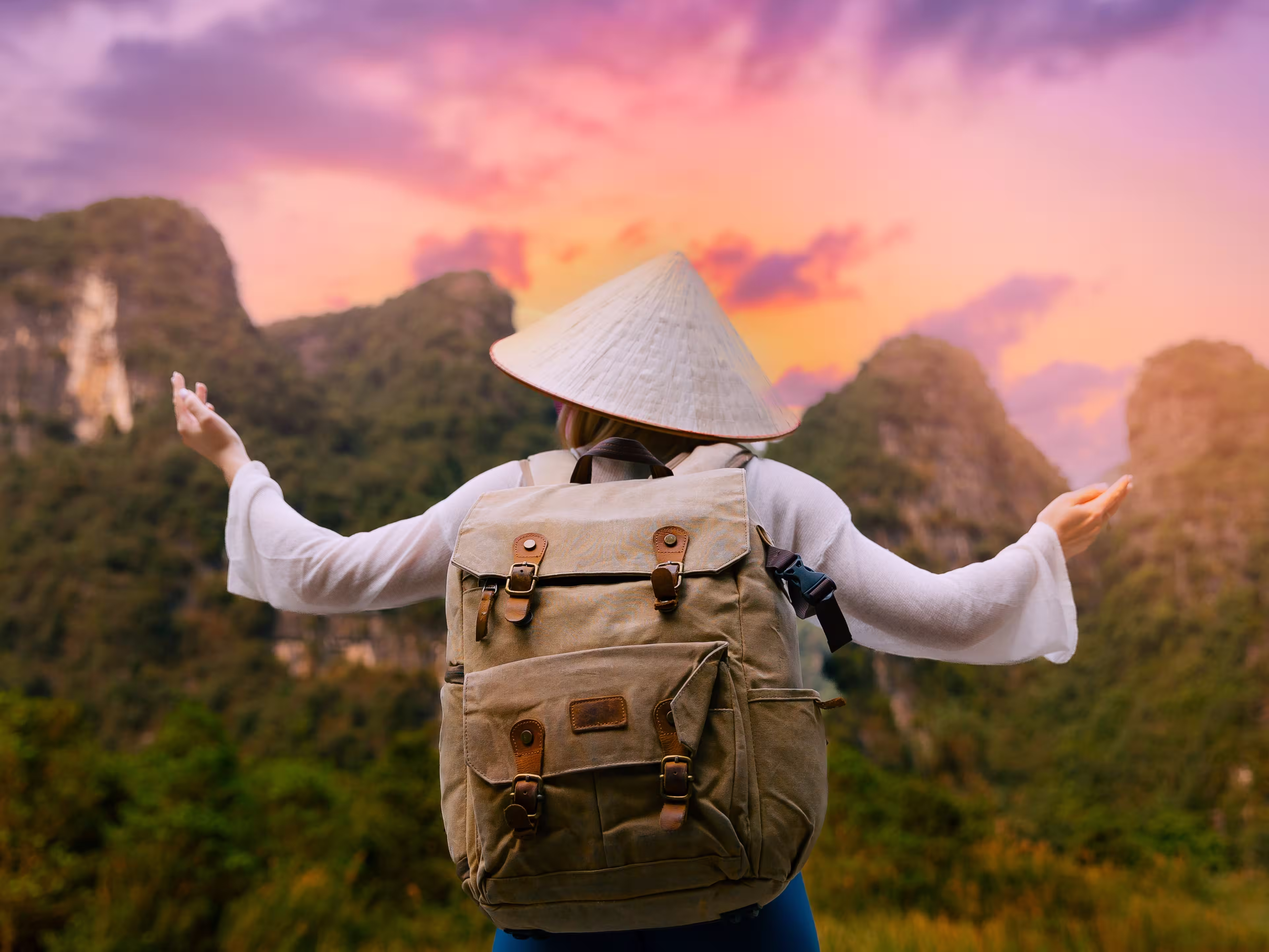 Female traveler with backpack at sunset in Tam Coc National Park Ninh Binh, Vietnam mountains.
