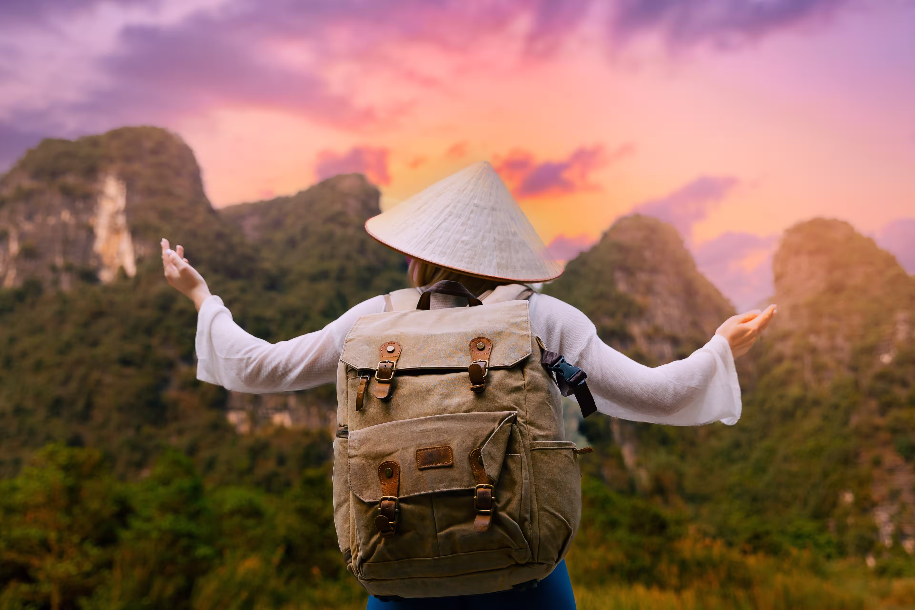 Female traveler with backpack at sunset in Tam Coc National Park Ninh Binh, Vietnam mountains.