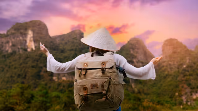 Female traveler with backpack at sunset in Tam Coc National Park Ninh Binh, Vietnam mountains.