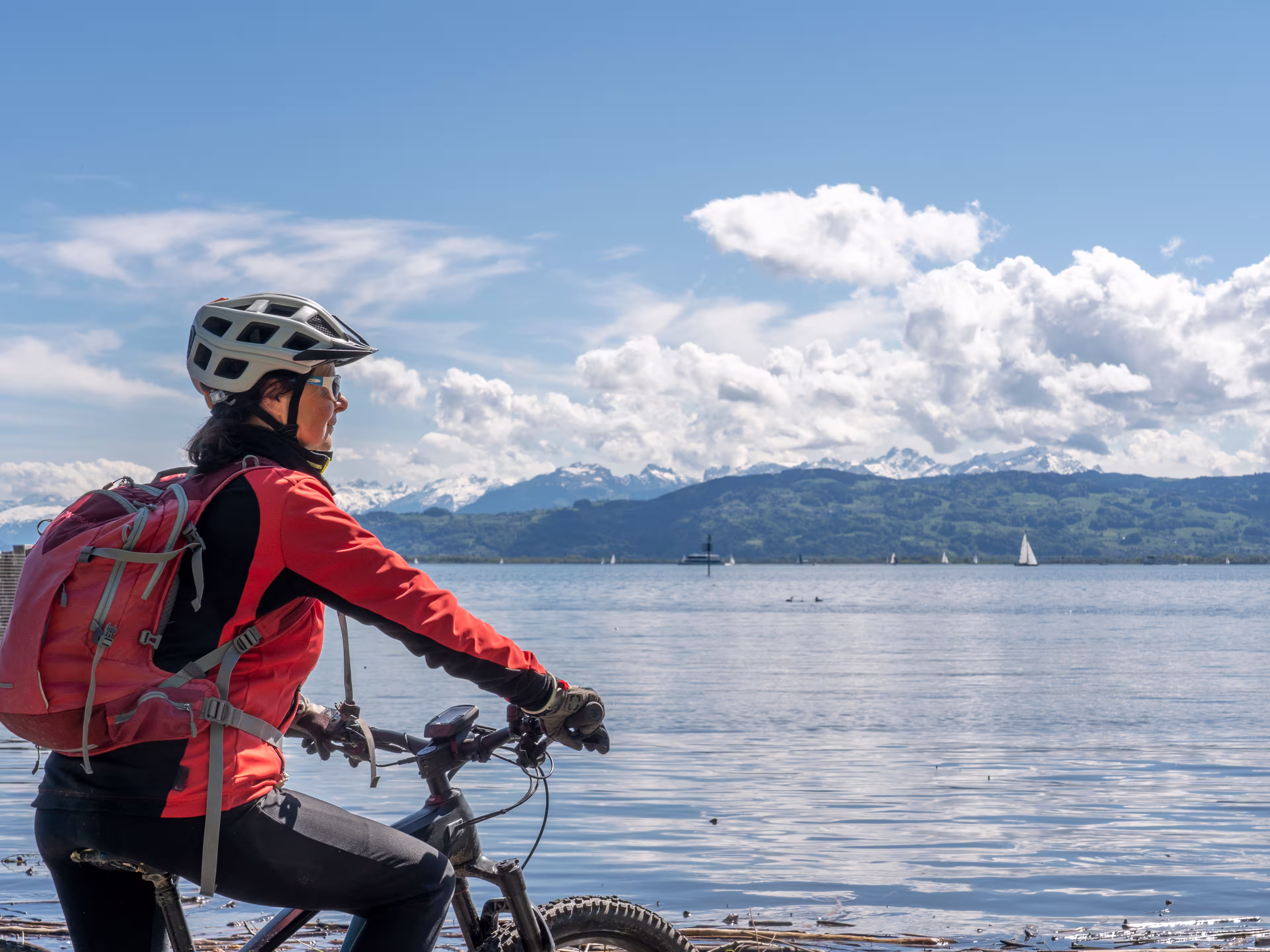 happy, active senior woman admiring a awesome view over Lake Constance with snow capped Swiss mountains in background
