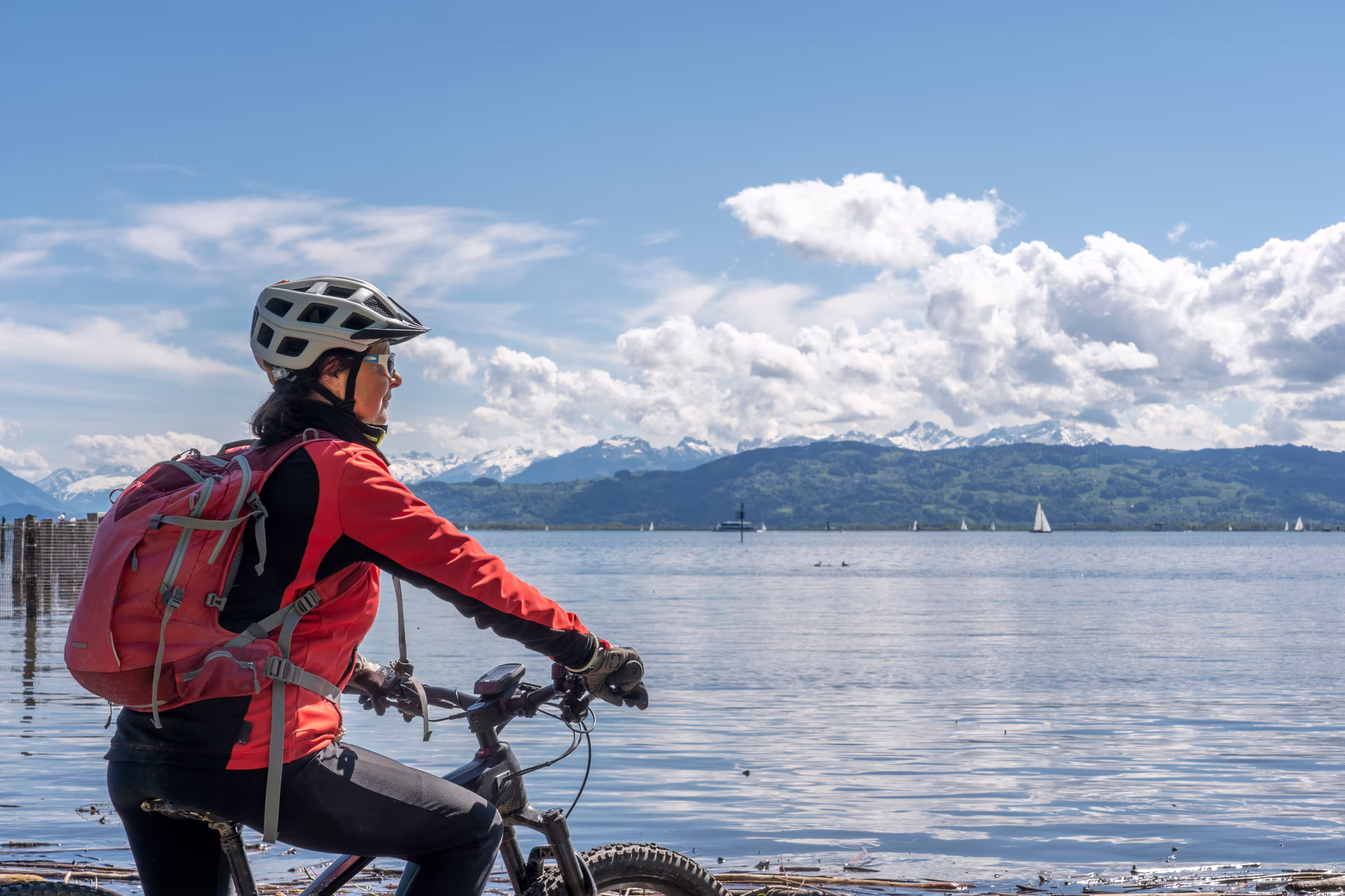 happy, active senior woman admiring a awesome view over Lake Constance with snow capped Swiss mountains in background