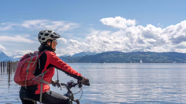 happy, active senior woman admiring a awesome view over Lake Constance with snow capped Swiss mountains in background