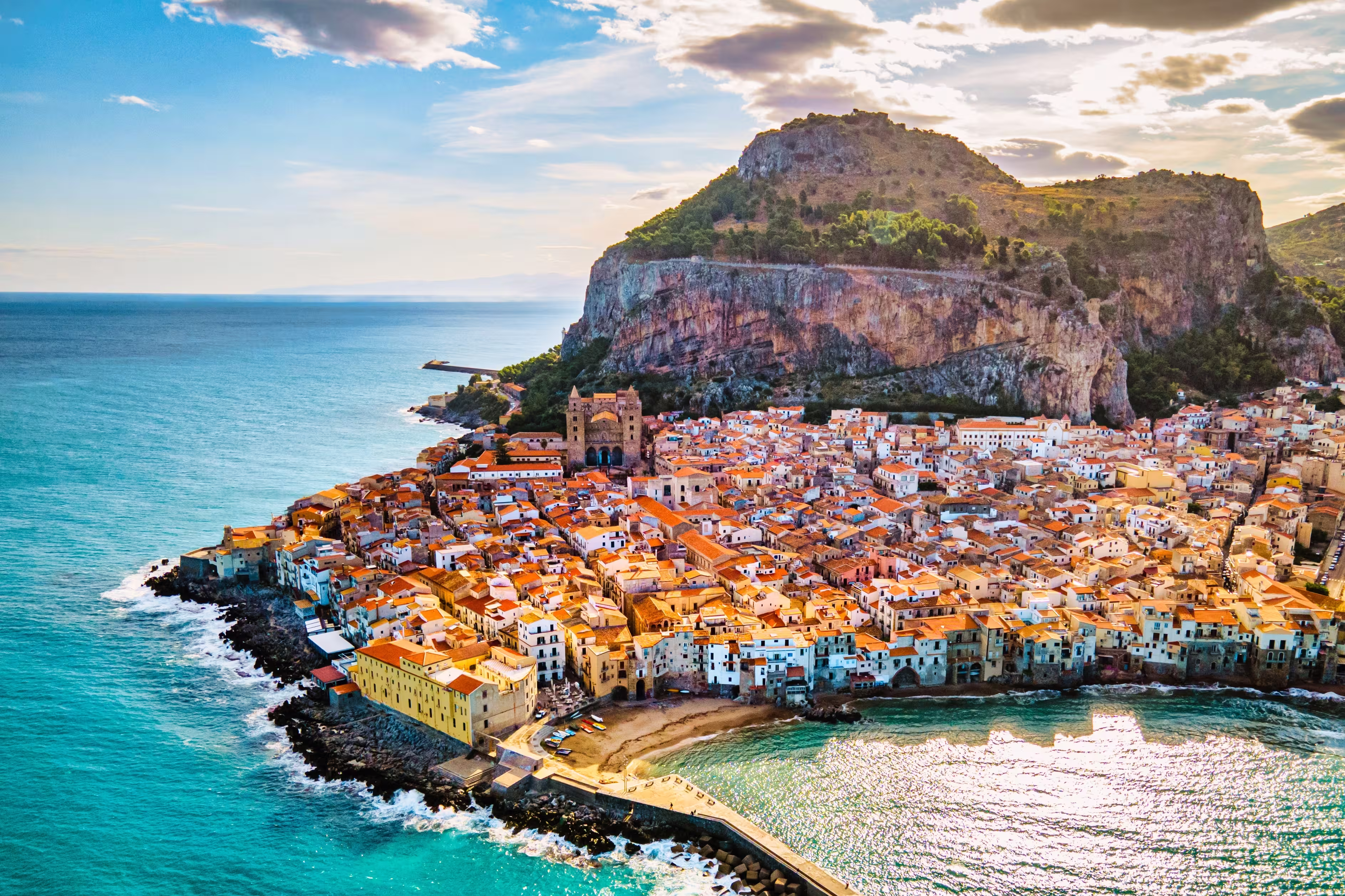 Drone view from above at the old town of Cefalu at sunset, medieval village of Sicily island, Province of Palermo, Italy. Europe. Cathedral of Cefalu