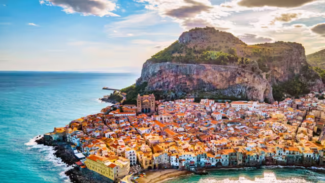 Drone view from above at the old town of Cefalu at sunset, medieval village of Sicily island, Province of Palermo, Italy. Europe. Cathedral of Cefalu