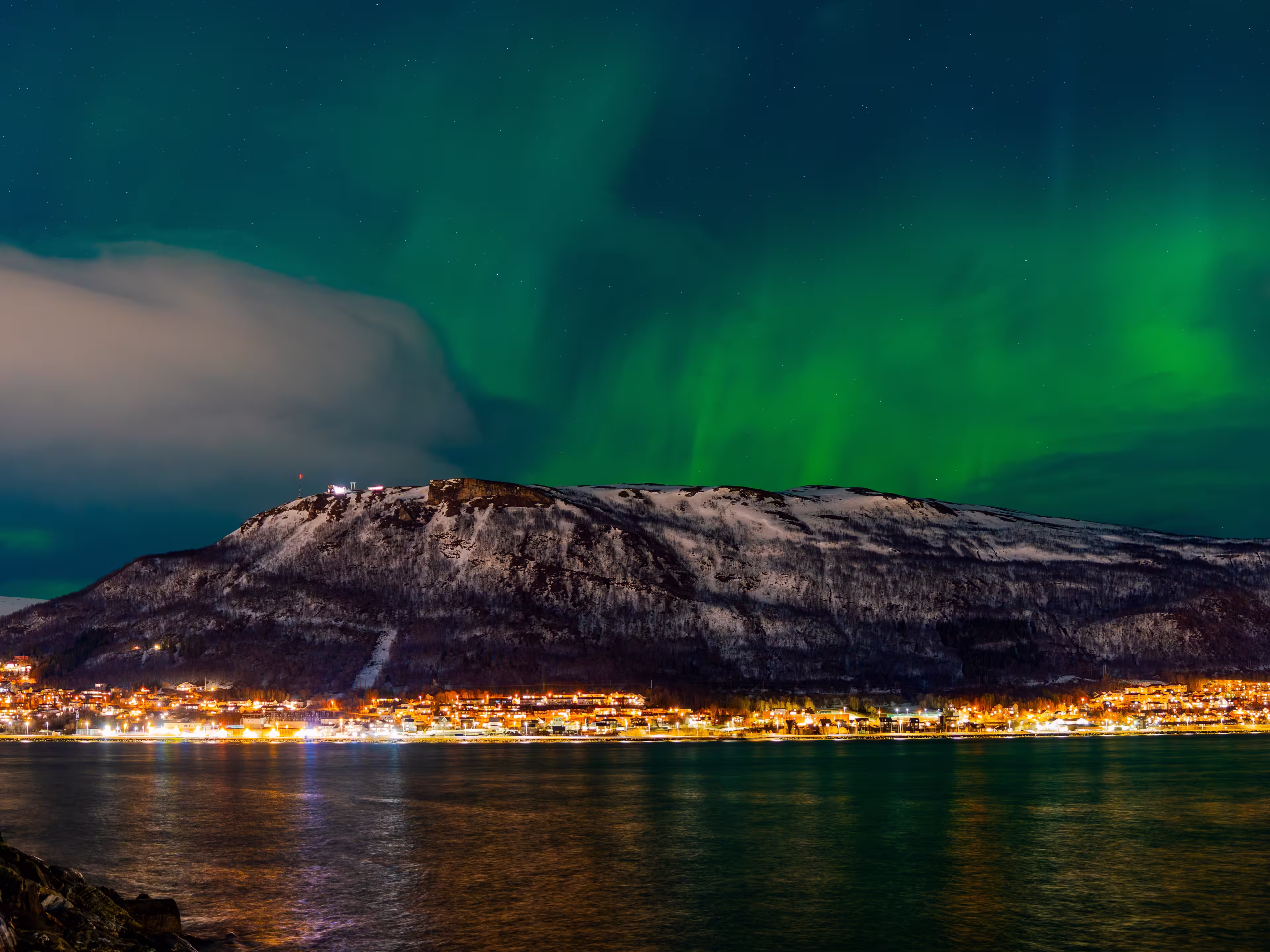 Tromsø, Troms, Norway - 28 February 2025 - Glimpse of Tromsø with the sky lit up by the Northern Lights
