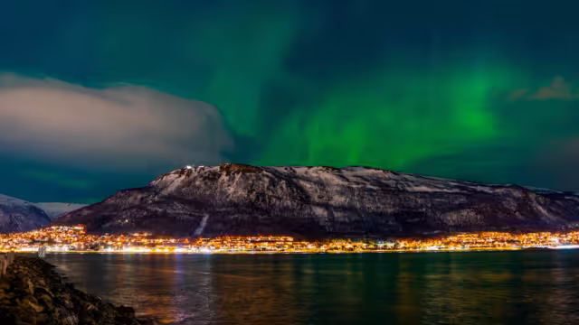 Tromsø, Troms, Norway - 28 February 2025 - Glimpse of Tromsø with the sky lit up by the Northern Lights