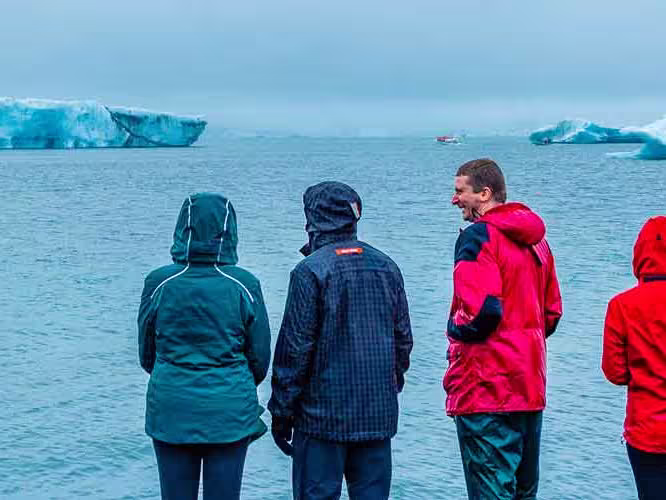 Group of travellers look at Jokulsarlon Glacier from the coastline