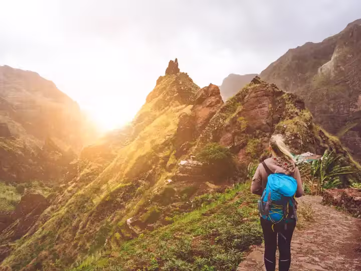 Girl walking down along the trekking route to verdant Xo-Xo valley. Warm sunlight seable on horizont. Santo Antao Island Cape Verde.