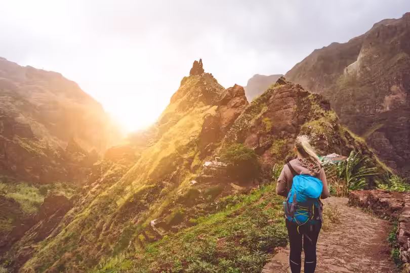 Girl walking down along the trekking route to verdant Xo-Xo valley. Warm sunlight seable on horizont. Santo Antao Island Cape Verde.