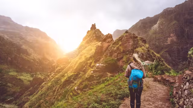 Girl walking down along the trekking route to verdant Xo-Xo valley. Warm sunlight seable on horizont. Santo Antao Island Cape Verde.
