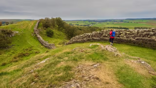 Distant view of Female traveller walking along Hadrian's Wall on a gloomy day in England, U.K.
