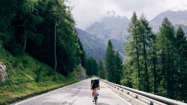 Professioneller Radfahrer mit schnellem und leichtem Kohlenstoff-Fahrrad steigt in den Alpen-Dolomiten auf die Bergstraße ab.